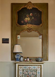 a table with a lamp, mirror and painting on the wall