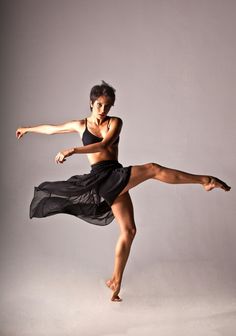 a woman in black dress dancing on grey background