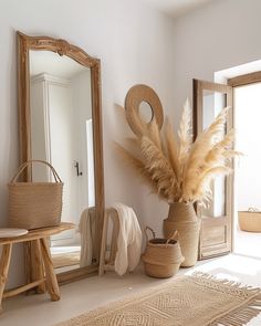 a large mirror sitting on top of a wooden table next to a vase filled with dry grass