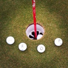 a golf hole with four white balls in it and a red flag sticking out of the hole