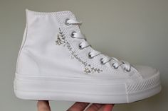 This pair of Converse canvas all white high tops with platform sole, with ivory woven badge is embroidered with green foliage and white/ivory/off white florals to suit any bride.  The shoes can be embroidered with the wreath alone around the badge on the inside facing part of the shoe, the name on the outer side of the shoes only or both.  Please ensure the correct size is selected, or if converting to UK sizing, ensure the correct conversion has been made to UK sizing and selected accordingly. White Converse For Wedding, White Wedding Converse, All White Platform Converse, White Sneakers Wedding, Bride Converse Shoes, Bridal Converse Shoes, Platform Converse High Tops, Wedding Sneakers For Bride, Bride Converse