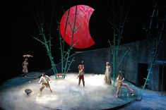 the performers are performing on stage in front of an object that looks like a red ball