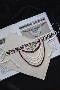 the bead work is laid out on top of an open book with string and thread