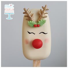 a close up of a cake on a stick with reindeer noses and holly wreaths