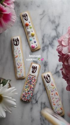 four decorated cookies sitting on top of a marble table next to pink flowers and scissors