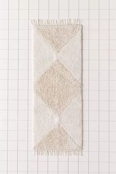 a white rug on top of a tile floor next to a wall with grids