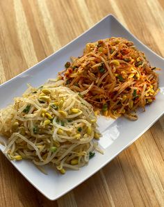 a white plate topped with noodles and vegetables on top of a wooden table next to a fork