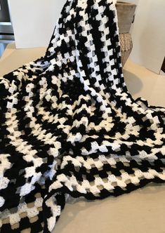 a black and white crocheted blanket sitting on top of a table next to a basket