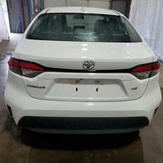 the back end of a white car parked in a garage