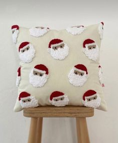 a pillow with santa claus on it sitting on a wooden stool in front of a white wall