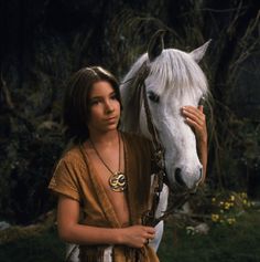 a woman is standing next to a white horse