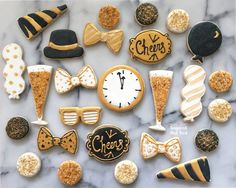 decorated cookies arranged in the shape of bow ties, hats, and other items on a marble surface