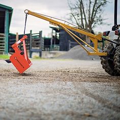 a tractor with a fork attached to it and an orange sign on the ground in front of it