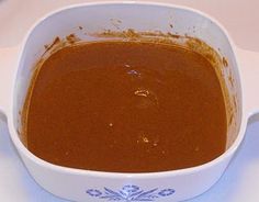 a white bowl filled with brown liquid on top of a table