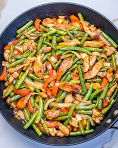 stir fry with chicken, green beans and peppers in a skillet on a marble countertop