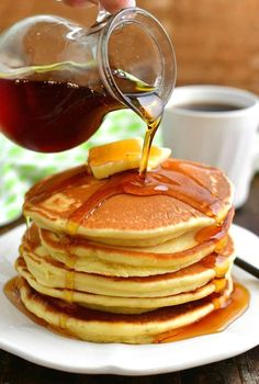 pancakes with syrup being poured onto them and stacked on top of each other, ready to be eaten