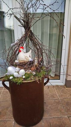 a potted plant with branches, eggs and a chicken sitting on top of it