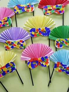 many colorful paper fans are arranged on top of each other, with black sticks sticking out of them