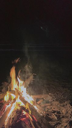 a campfire is lit up at night on the ground with no one around it