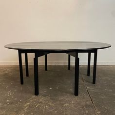 a round table with two black legs on concrete floor