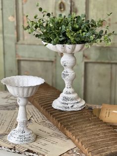 two white vases sitting on top of a wooden table next to an open book