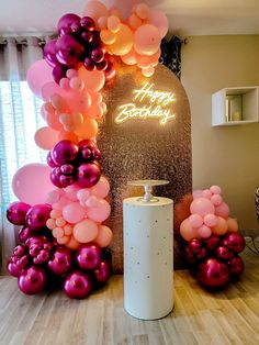 a birthday party with balloons and streamers in the shape of an arch on top of a table