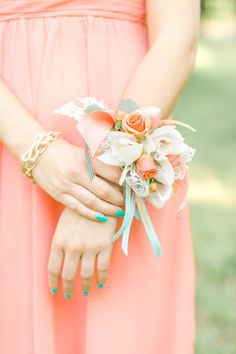 a woman in an orange dress holding a wedding bouquet with flowers on it's wrist