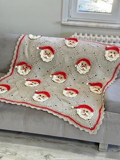 a crocheted blanket with santas on it sitting on a couch next to a window