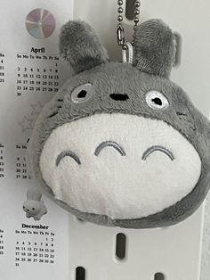 a stuffed animal keychain hanging on a wall with a calendar in the background