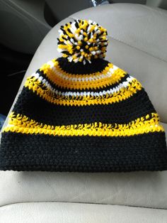 a black and yellow knitted hat sitting on top of a car seat