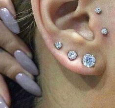 a woman's ear with three different piercings on her left side and two smaller ones