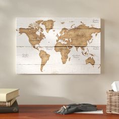 a wooden world map hanging on the wall above a desk with books and other items