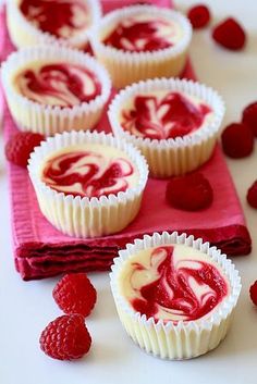 raspberry swirl cupcakes on a pink napkin with fresh raspberries scattered around them