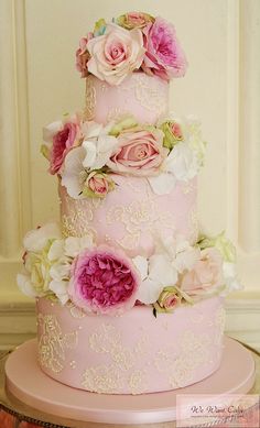 a three tiered cake with pink and white flowers