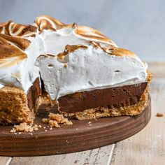 a piece of chocolate pie with white frosting on a cutting board next to it