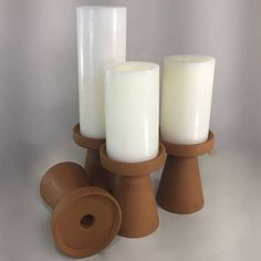 three candles sitting on top of each other in front of a white background and brown stand