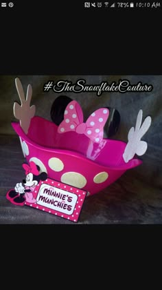 a pink minnie mouse cup with polka dots and bows on the top, next to a sign that says minnie's munchies