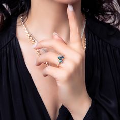 a woman in black shirt holding her hand up to her face with ring on it