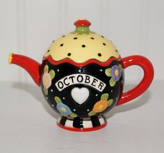 a ceramic teapot with the word october painted on it's front and sides