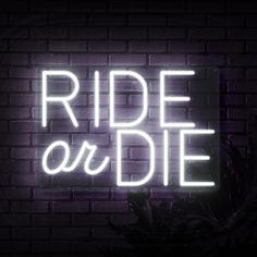 a neon sign that reads ride or die on a brick wall with plants in the background