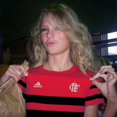 a woman in a red and black shirt is holding a brown bag