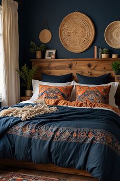 a bed with blue and orange comforter in a bedroom next to a window filled with potted plants