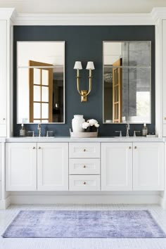 a bathroom with two sinks, mirrors and rug on the floor in front of them