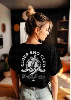 "*This shirt has a design on the FRONT & BACK* Step back in time and relive the golden era of emo music with our Elder Emo Music T-Shirt. This comfy tee is the perfect choice for those who still carry the spirit of emo in their hearts. Featuring a captivating design of a beautifully detailed skull and a defiant \"rock on\" hand gesture, this shirt is a must-have for any elder emo enthusiast. Whether you're searching for an emo gift or wanting to express your undying love for the emo subculture, this scene shirt is the ultimate statement piece. Wear it proudly to the When We Were Young Festival or any other music event, and let the world know that your emo spirit is alive and thriving. It's not just a phase; it's a way of life. Embrace the everlasting emo culture with our Elder Emo Shirt an Cheap Alternative Style T-shirt For Music Festival, Goth Tee Shirt, Cheap Emo Tops For Concert, Cheap Emo Fan Merchandise T-shirt, Elder Emo Shirt, Adult Punk Outfits, Elder Emo Aesthetic, All Time Low Concert Outfit, Emo Band Tees