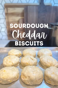 doughnuts sitting on top of a baking sheet with the words, sourdough cheddari biscuits