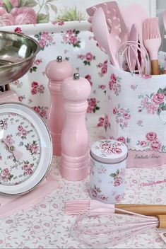 pink kitchen utensils are sitting on a table next to a clock and measuring spoons