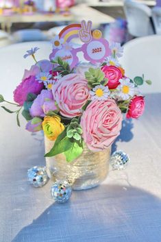 a vase filled with lots of flowers on top of a blue tablecloth covered table