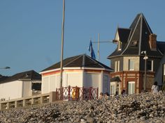 some houses on the beach with people walking around