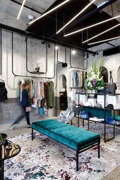 the inside of a clothing store with lots of clothes on display and a bench in front of it