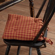 a red and white checkered pillow sitting on top of a wooden chair next to a table